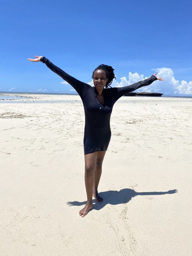 Young African lady happily stretching arms at White Sandy Beach at Kisite Mpunguti