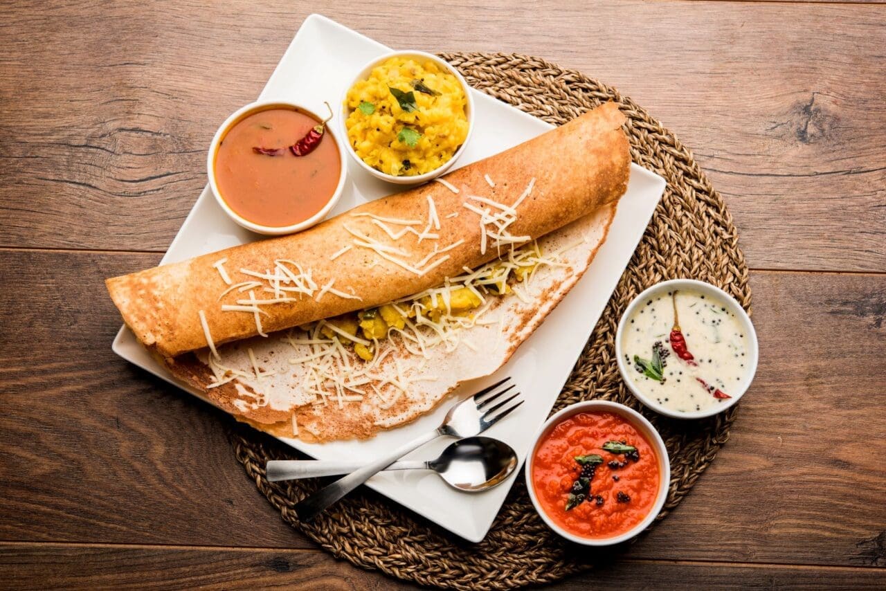 A plateful with Cheese masala dosa and dipping sauces on the side