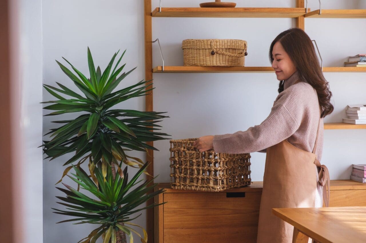 Portrait image of a woman holding a wooden basket while cleaning house