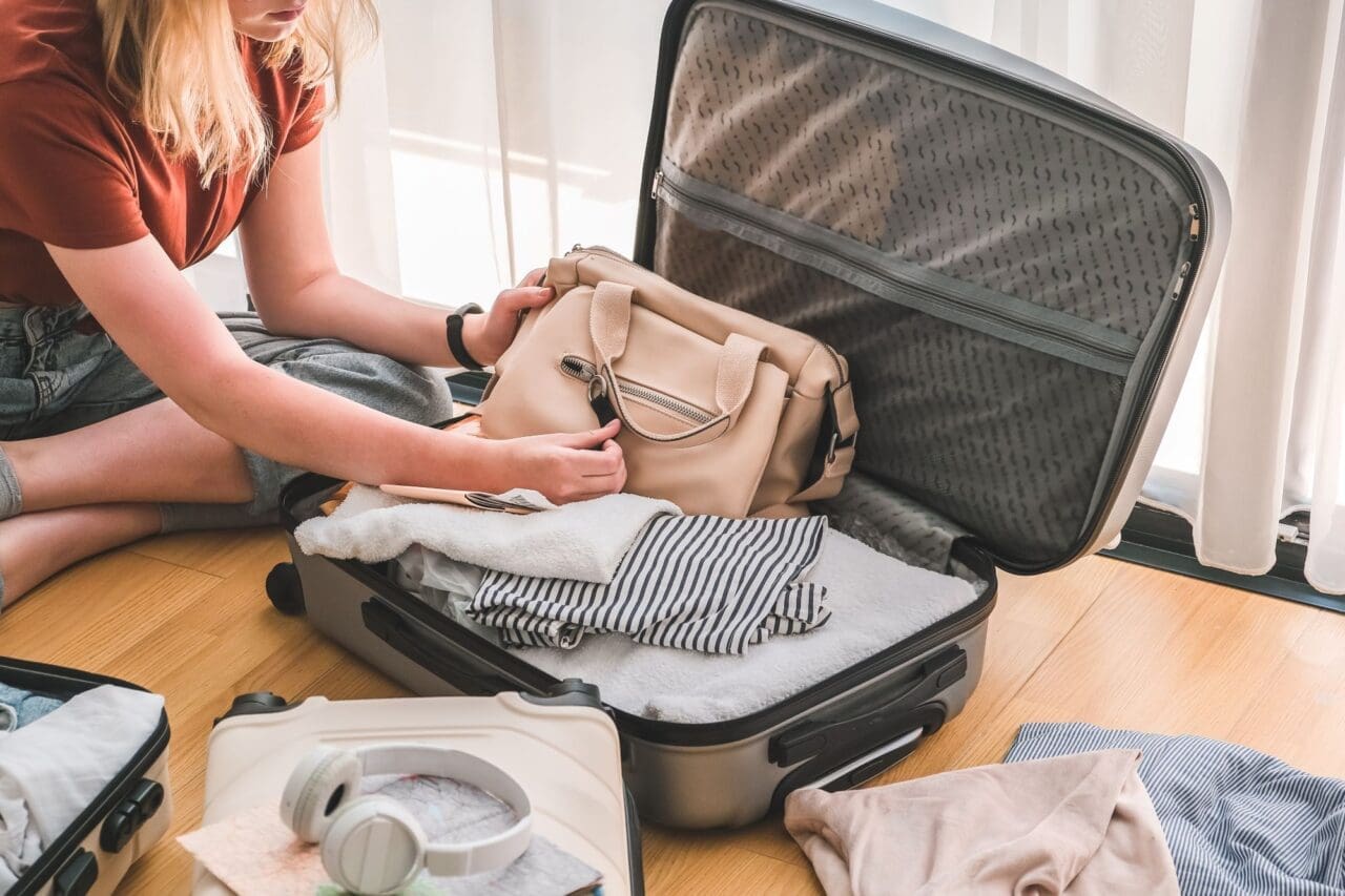 Girl packing luggage in suitcase and travel documents
