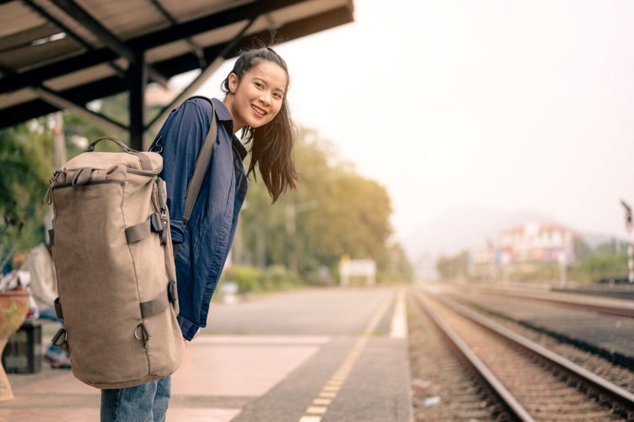 Portrait of female passenger with backpack on railroad platform in waiting for train