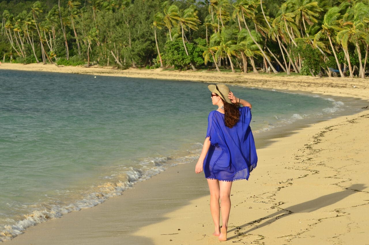 Tourist woman walks along a remote beach of an Island in Fiji.